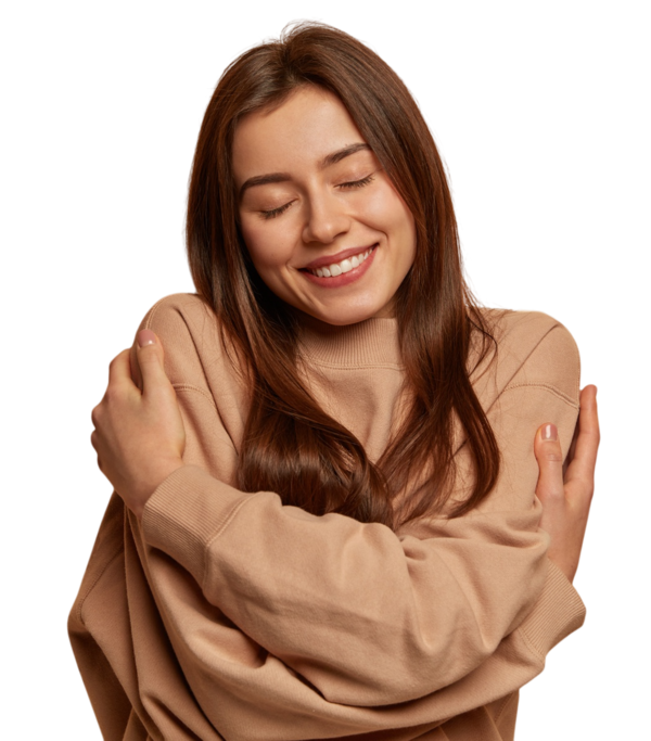 Mulher sorrindo e se abraçando, cabelos longos castanhos, suéter bege, expressão de acolhimento e bem-estar, fundo transparente